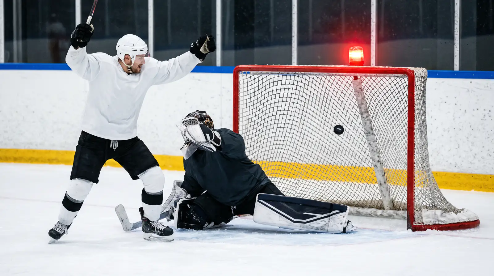 Hockey player scoring the opening goal of a game past the opposing goaltender