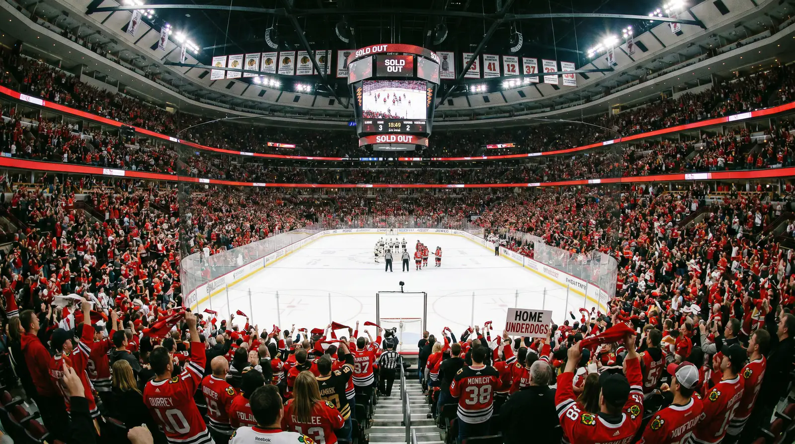 Hockey arena packed with home fans creating a wall of noise behind the home underdog team