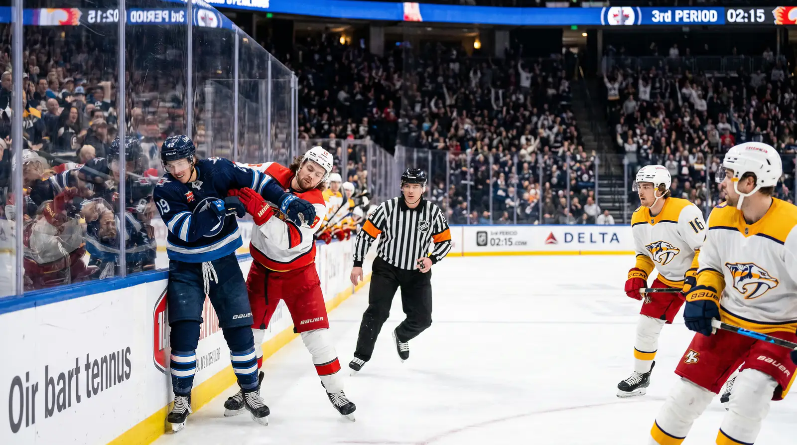 Two NHL players engaged in a physical confrontation near the boards during a rivalry game