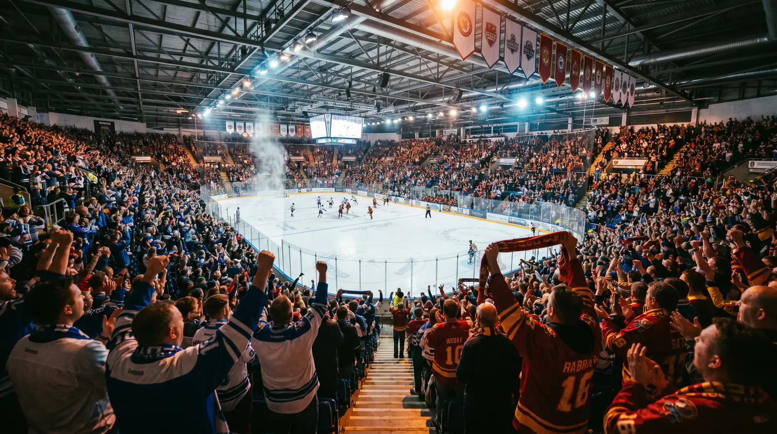 Indoor ice hockey arena filled with cheering fans during a professional EIHL match